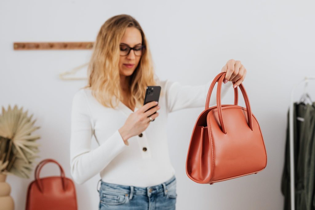 A Woman in White Long Sleeves Taking Photos of a Handbag
