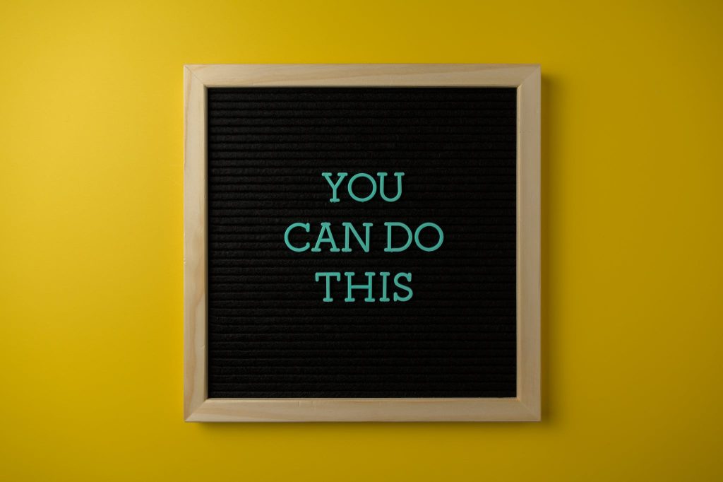 Framed Board with a Motivational Slogan on a Yellow Wall 